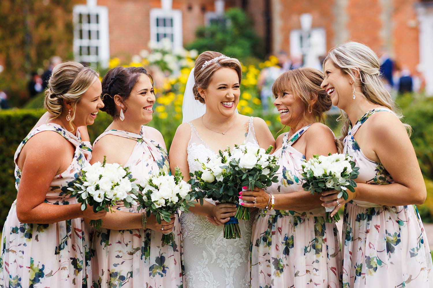 Bride shares a laugh with her bridesmaids whilst all holding bouquets