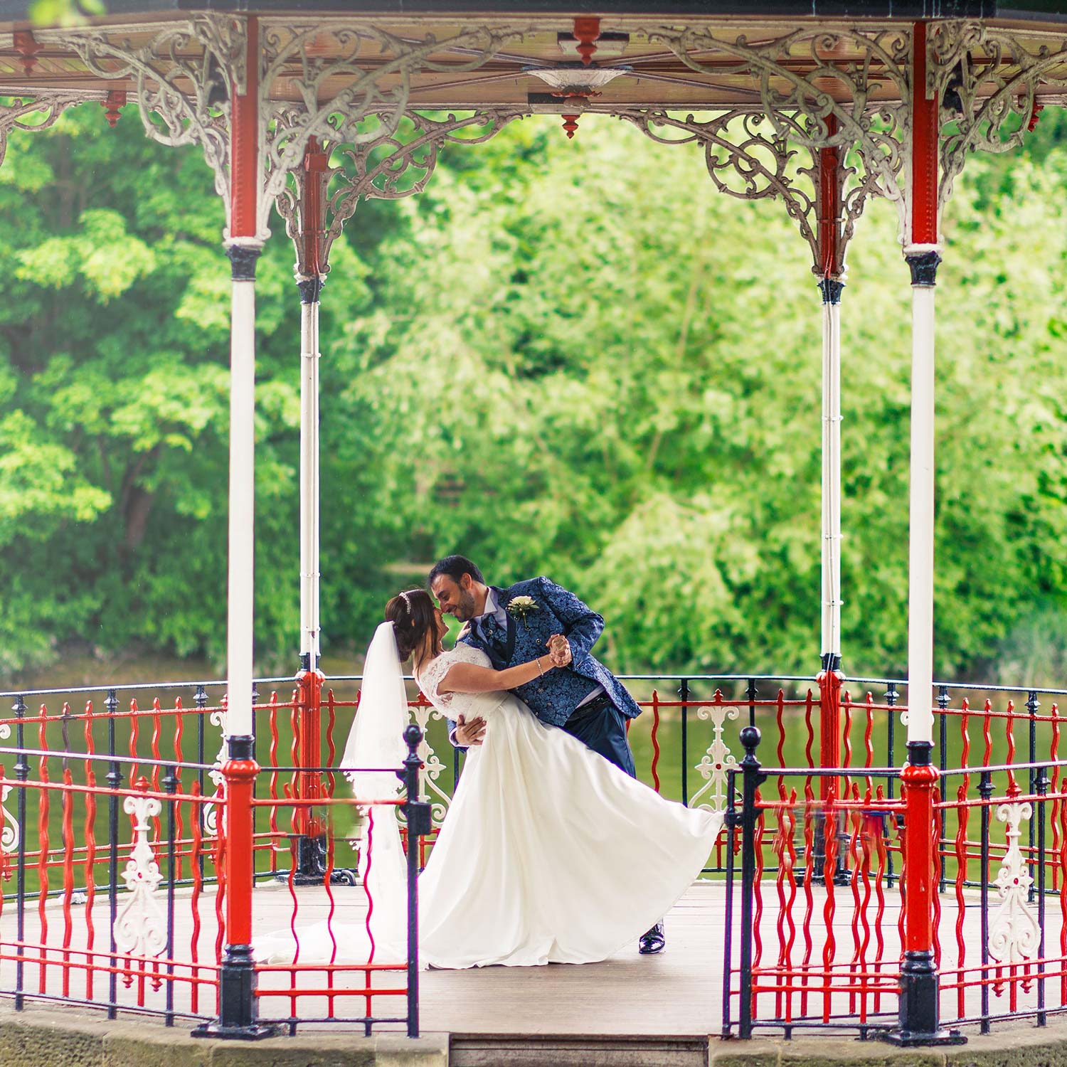 Groom dips bride under a large white and red bandstand
