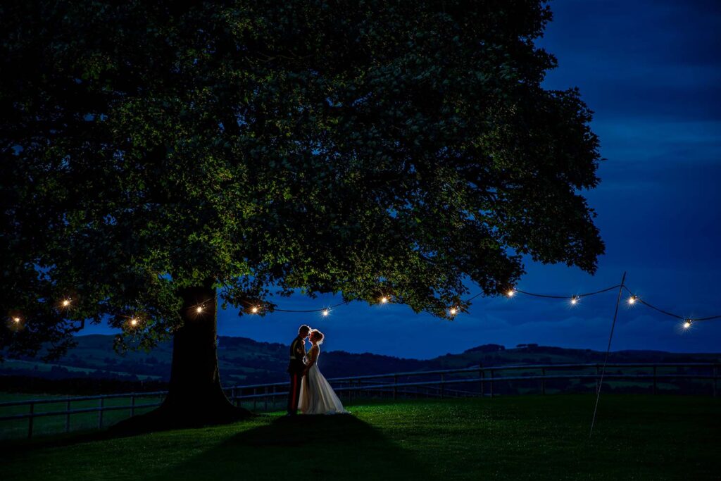 Night time photo of bride and groom under the tree at Heaton House Farm in Cheshire
