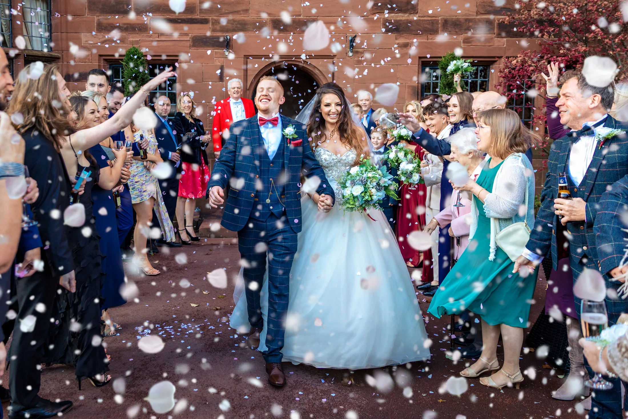 Newlyweds walking through confetti at a North West wedding at Abbey House Hotel, Cumbria