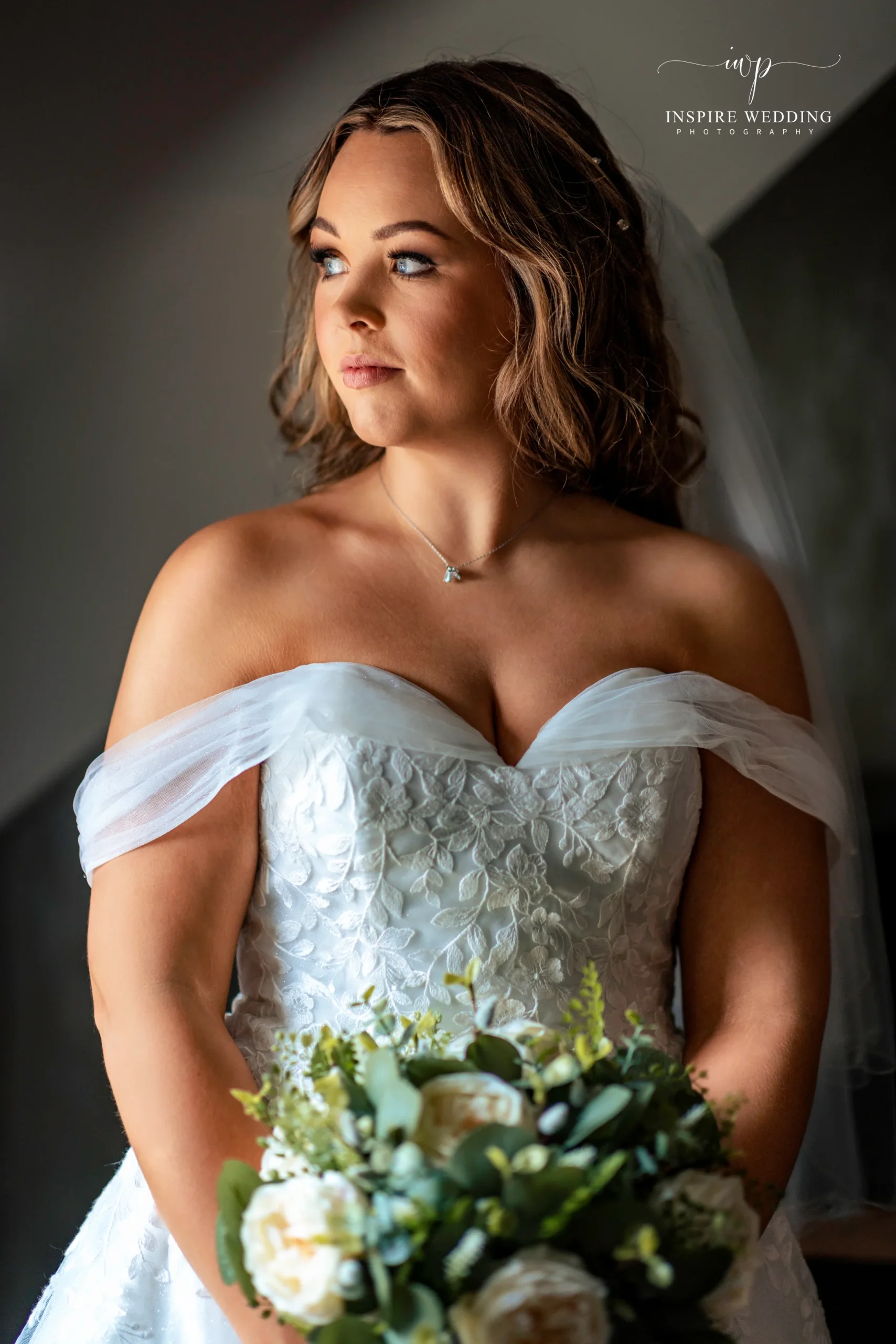 A bride holding a white bouquet in soft window light at the Grosvenor Pulford