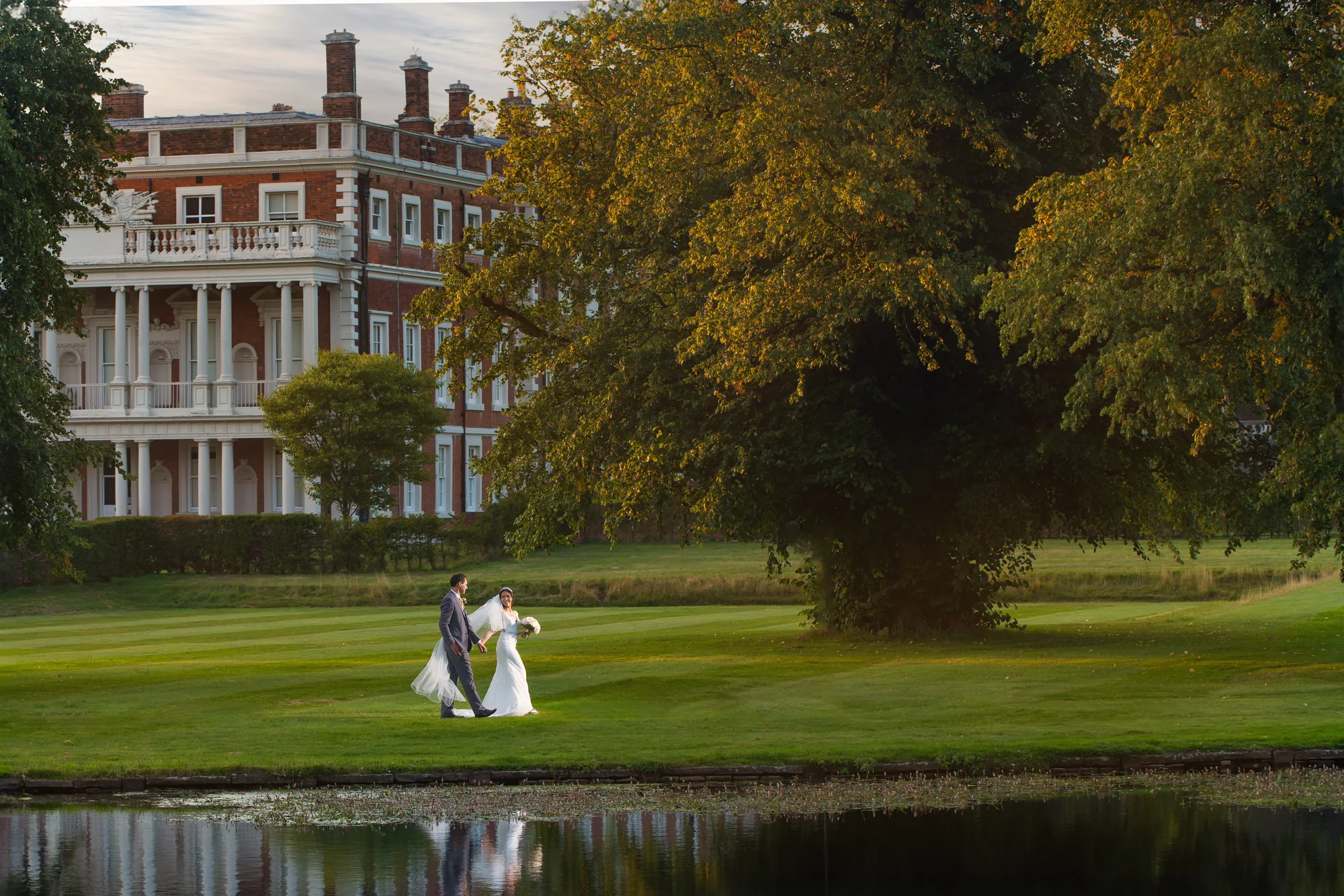 Newlyweds walking across the grounds at Knowsley Hall