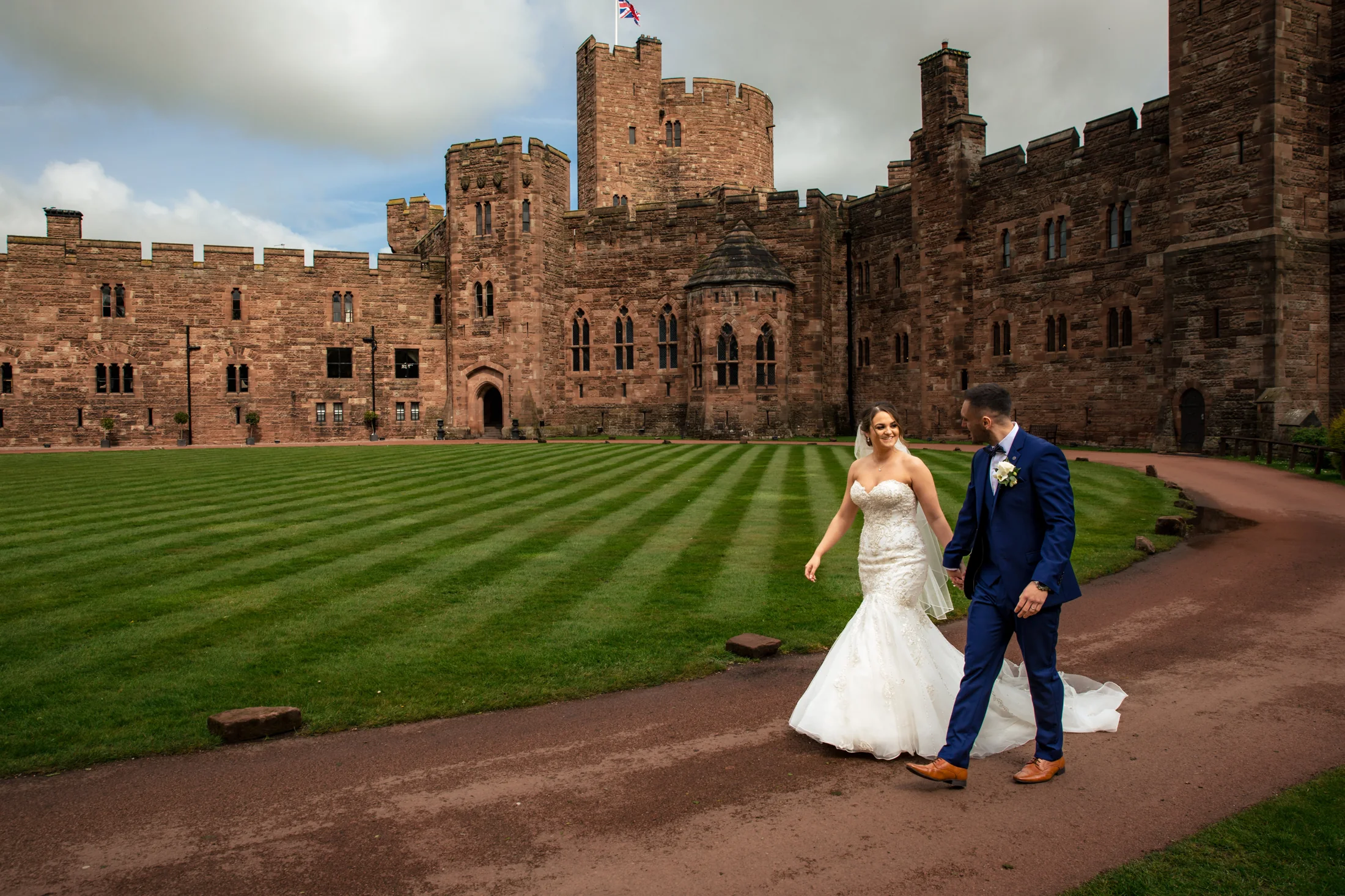 A couple walking hand in hand at their Cheshire wedding at Peckforton Castle