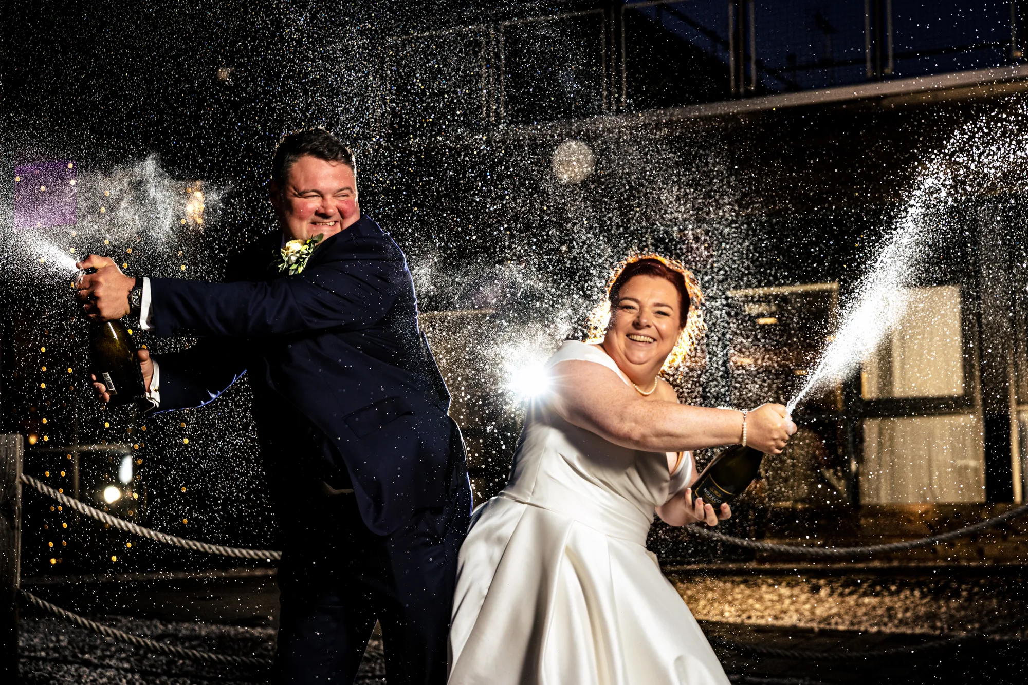 Newlyweds spraying champagne outside The Lake House Waterloo
